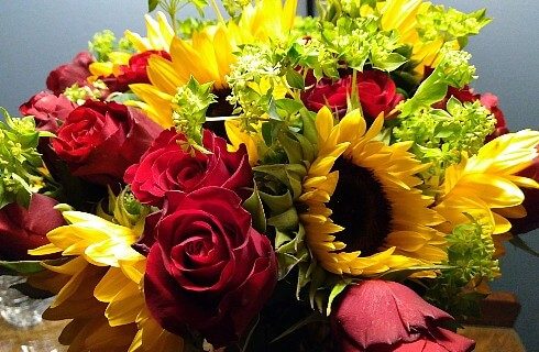 Lovely bouquet of red roses, large yellow sunflowers and greenery.