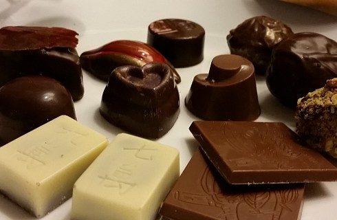 White plate with white, milk and dark chocolates in a variety of shapes and sizes.