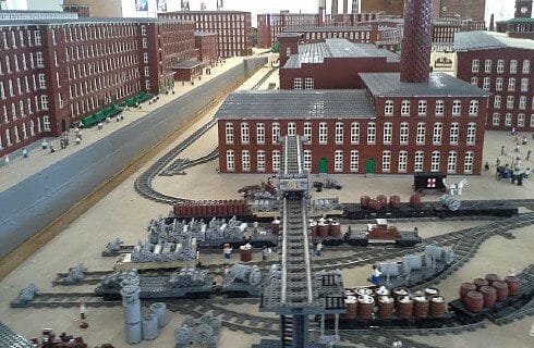 Table at a museum showing a model to scale of a town with many red buildings and a train track.