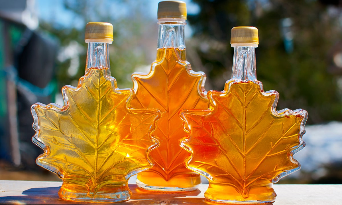 3 bottles in maple leaf shape filled with an amber colored liquid