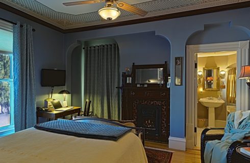 Elegant guest room with slate blue walls, curved doorways, decorative ceiling and antique furnishings